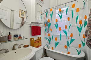 Bathroom featuring a sink, toilet, a decorative wall, and a wainscoted wall
