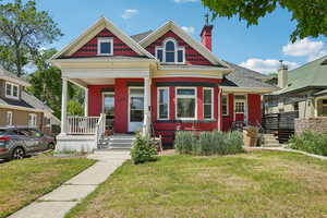 View of front of property with covered porch, a front lawn, and roof with shingles