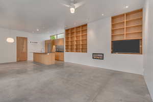 Open living space with finished concrete floors and builtin book shelves and fireplace.