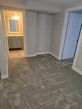 Unfurnished bedroom featuring carpet floors, baseboards, a sink, and ensuite bathroom