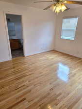 Empty room featuring light wood finished floors, baseboards, and a ceiling fan