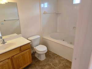 Bathroom with toilet, vanity, tile patterned flooring, and washtub / shower combination