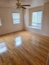 Empty room featuring healthy amount of natural light, light wood finished floors, baseboards, and a ceiling fan