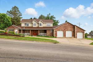 Traditional home with covered porch, driveway, an attached 3-car garage, and brick siding