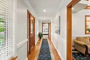 Entry hall featuring healthy amount of natural light, ornamental molding, light wood floors, a wainscoted wall, and recessed lighting