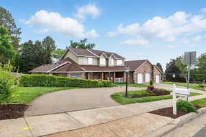 Traditional-style house featuring curved driveway, a porch, brick siding, and a 3-car garage
