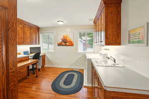 Laundry room featuring cabinet space, light wood flooring, an office area, and pull-out island / work table