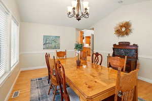 Dining space featuring lofted ceiling, light wood floors, a chandelier, and baseboards
