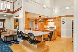 Kitchen with white oven, a high ceiling, range hood, paneled built in refrigerator, and a peninsula