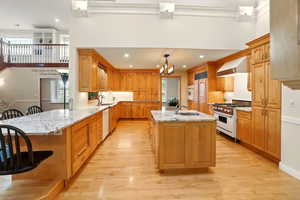 Kitchen featuring range with gas stovetop, range hood, dishwasher, a sink, and a chandelier