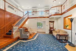 Living area with stairs, wood finished floors, a high ceiling, and baseboards