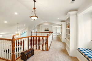 Balcony hall with light carpet, lofted ceiling, an upstairs landing, built-in bookcases, and recessed lighting