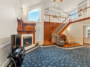 Living room featuring high vaulted ceiling, a ceiling fan, healthy amount of natural light, stairs, and a premium fireplace
