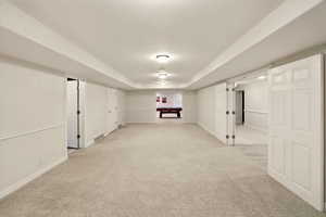 Finished basement featuring light colored carpet and baseboards, double doors to ADU