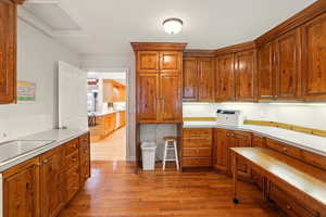 Laundry room featuring wood finished floors, cabinetry, light countertops, a sink, and pull-out island / work table