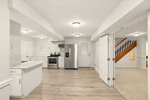 ADU kitchen featuring appliances with stainless steel finishes, white cabinets, light countertops, and light wood-style floors