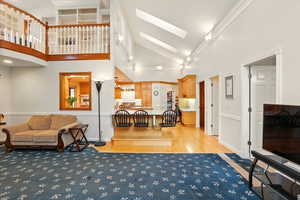 Living area with a skylight, light wood floors, and high vaulted ceiling