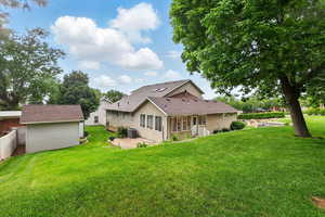 Rear view of property with a patio, a lawn, an outdoor storage shed, and central AC unit