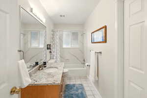 Bathroom featuring tile patterned floors, vanity, shower / bath combo with shower curtain, toilet, and baseboards