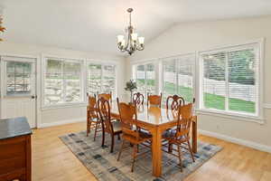 Dining room with plenty of natural light, a chandelier, light wood floors, and lofted ceiling