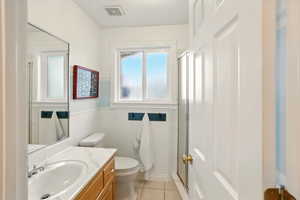 3/4 bathroom with tile patterned flooring, a shower stall, toilet, and vanity