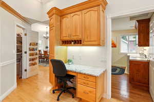 Office space featuring light wood flooring, and built in desk