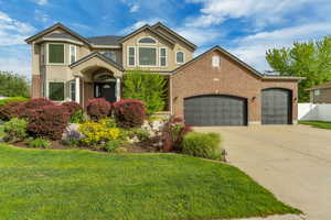 Traditional-style home featuring concrete driveway, an attached garage, stucco siding, and brick siding