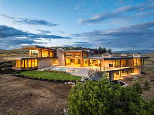 Rear view of property with an outdoor pool, a balcony, a patio area, and stone siding