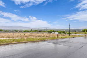 View of asphalt road featuring street lighting, a mountain view, and curbs