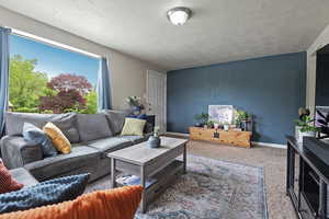 Carpeted living area featuring a textured ceiling and baseboards