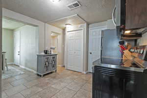 Kitchen featuring baseboards, stainless steel appliances, a textured ceiling, and light tile patterned flooring