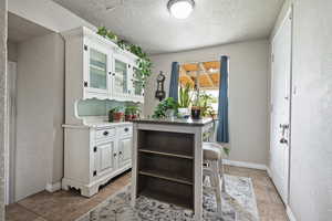 Kitchen with open shelves, glass insert cabinets, white cabinets, a textured ceiling, and baseboards