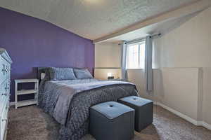 Bedroom featuring a textured wall, carpet, baseboards, and a textured ceiling