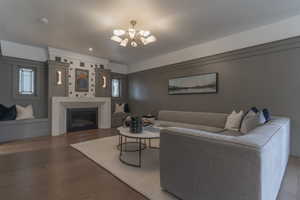 Living room featuring a chandelier, wood finished floors, a glass covered fireplace, and plenty of natural light