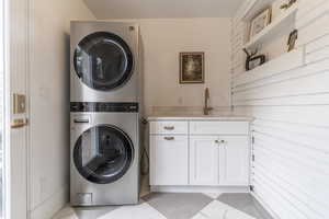 Clothes washing area with stacked washer and clothes dryer and cabinet space