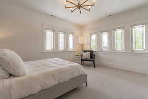 Carpeted bedroom featuring a chandelier and baseboards