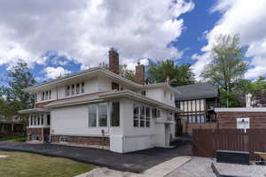 Rear view of property featuring stucco siding, fence, and a chimney