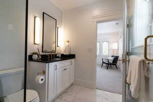 Bathroom featuring vanity, marble finish flooring, baseboards, and toilet