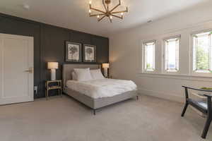 Bedroom with a chandelier, light colored carpet, and baseboards