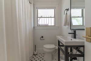 Bathroom with healthy amount of natural light, tile patterned floors, toilet, and vanity