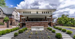 View of front of house with fence, stairs, brick siding, and stucco siding