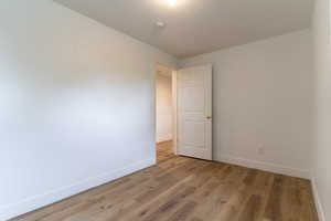 Unfurnished room featuring baseboards, a smoke detector, and light wood-style flooring