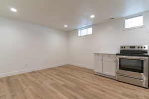 Kitchen featuring electric range, recessed lighting, light wood-style floors, white cabinets, and light countertops