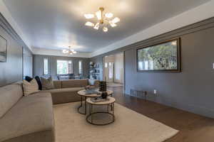 Living area with a chandelier, wood finished floors, and baseboards