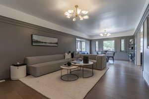 Living area with a chandelier, wood finished floors, and baseboards