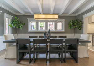Dining space with plenty of natural light, beamed ceiling, wood finished floors, wainscoting, and crown molding