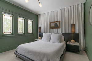 Carpeted bedroom featuring multiple windows and baseboards