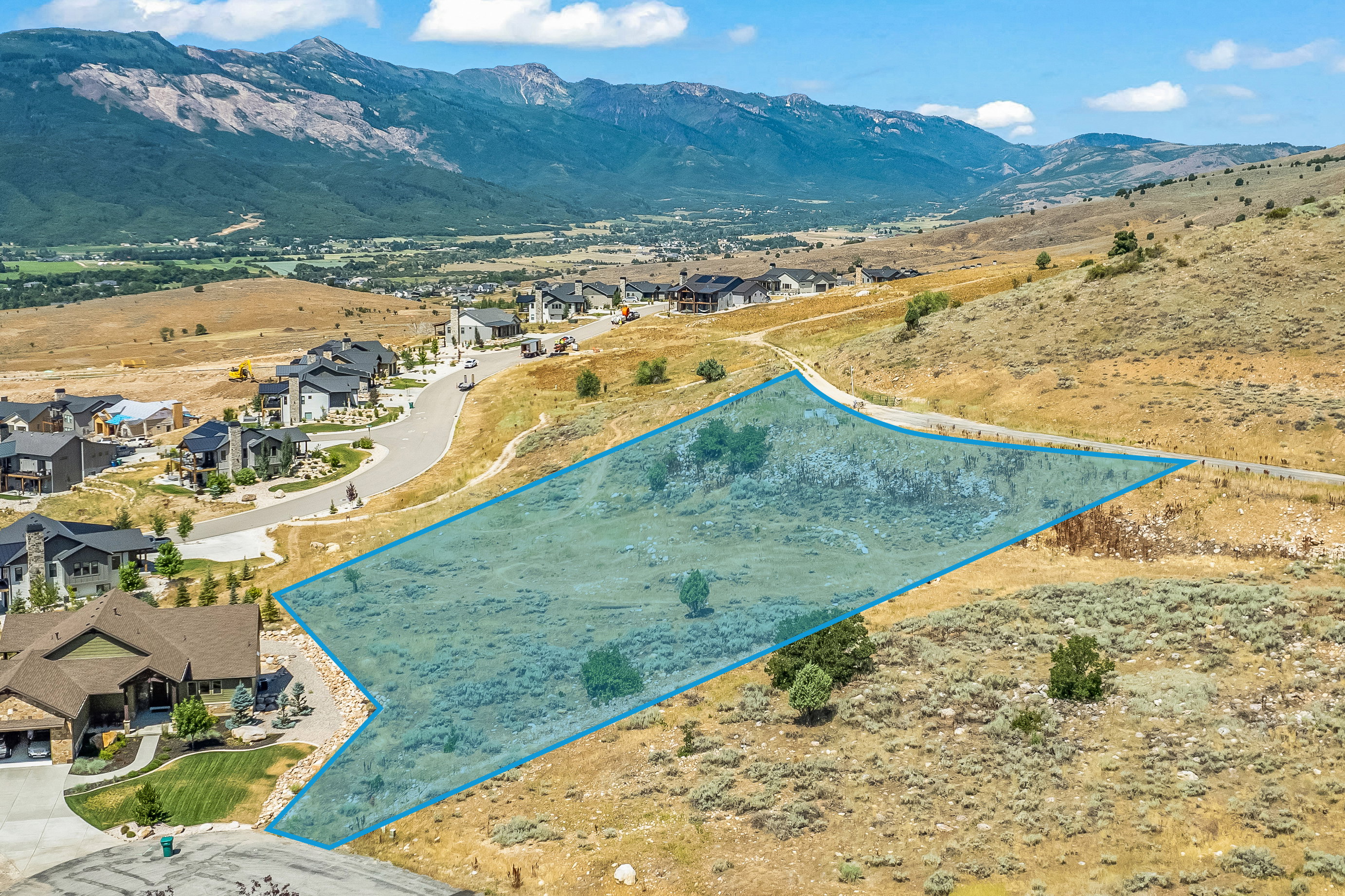 Aerial perspective of suburban area with property parcel outlined and mountains