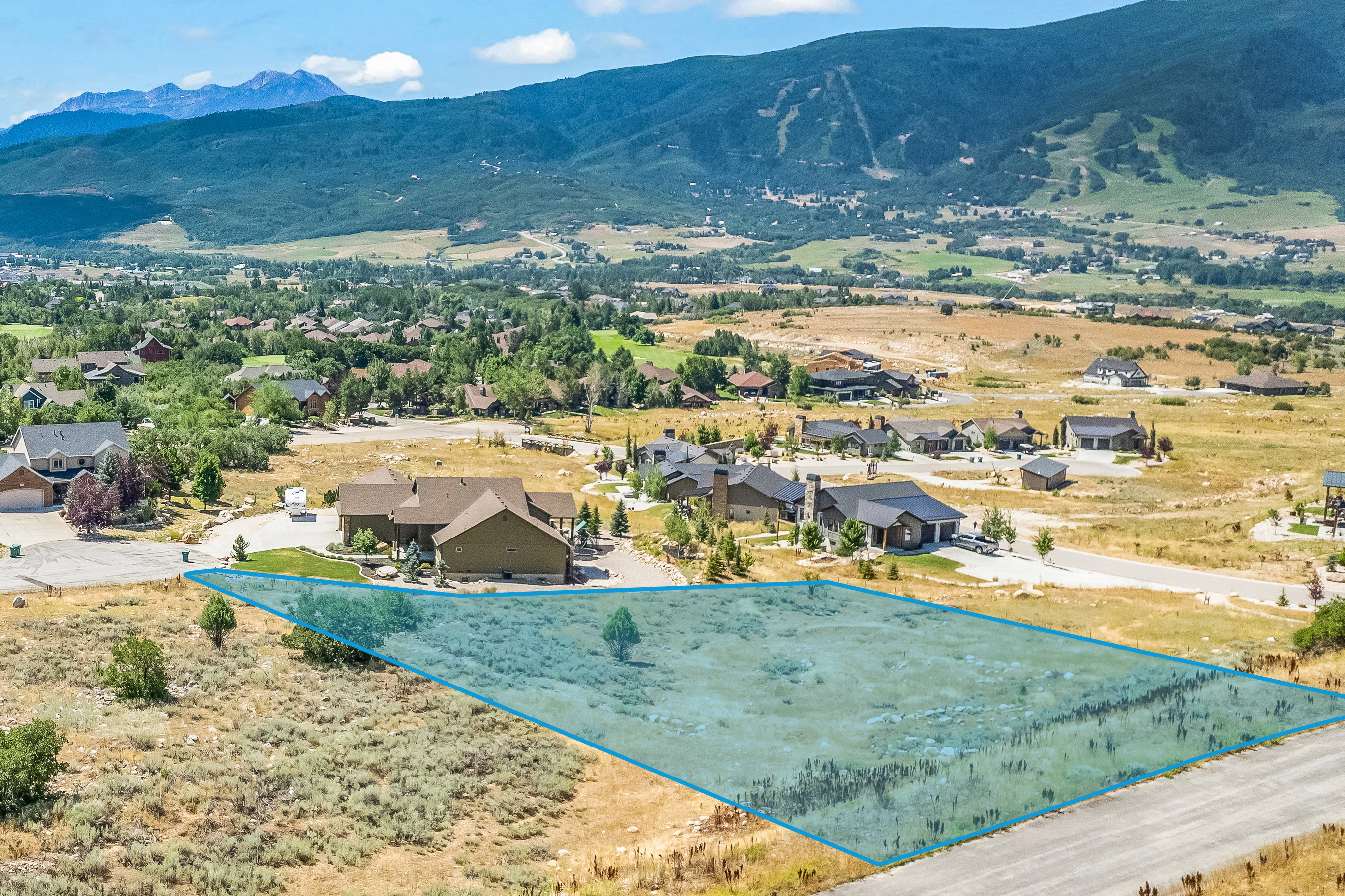 Aerial view of residential area with property parcel outlined and mountains