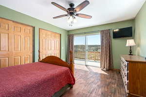 Barn upstairs apartment bedroom featuring access to outside, dark wood-type flooring, ceiling fan, two closets, and baseboards